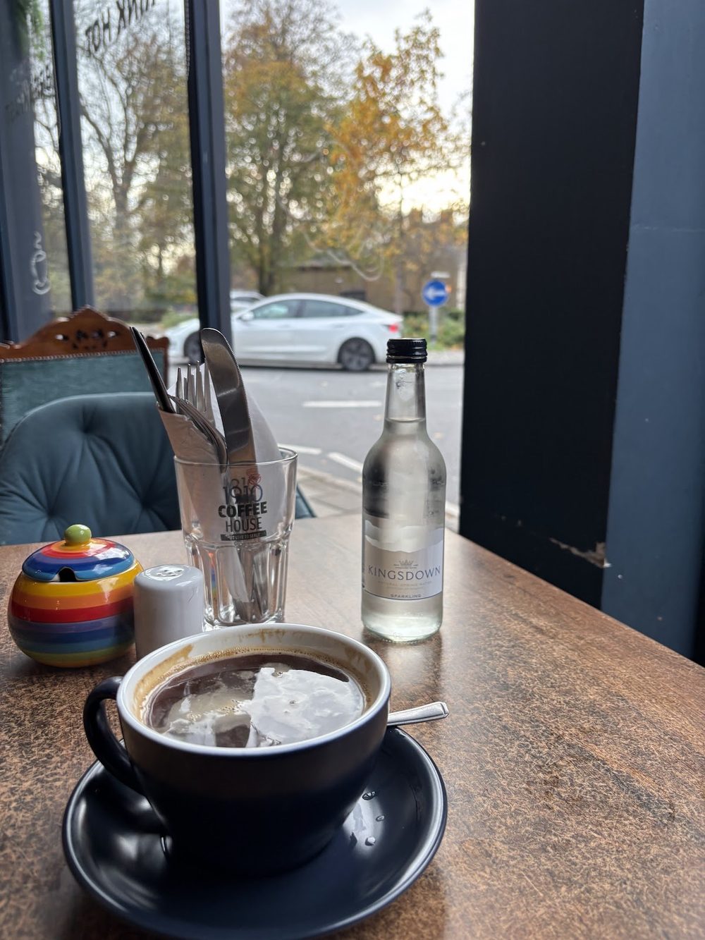A table by the window looking out onto the street and the trees outside