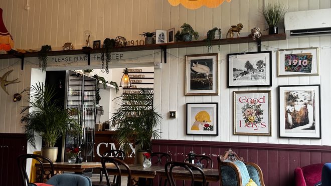 Coffee in the foreground with the lounge seating and picture wall behind