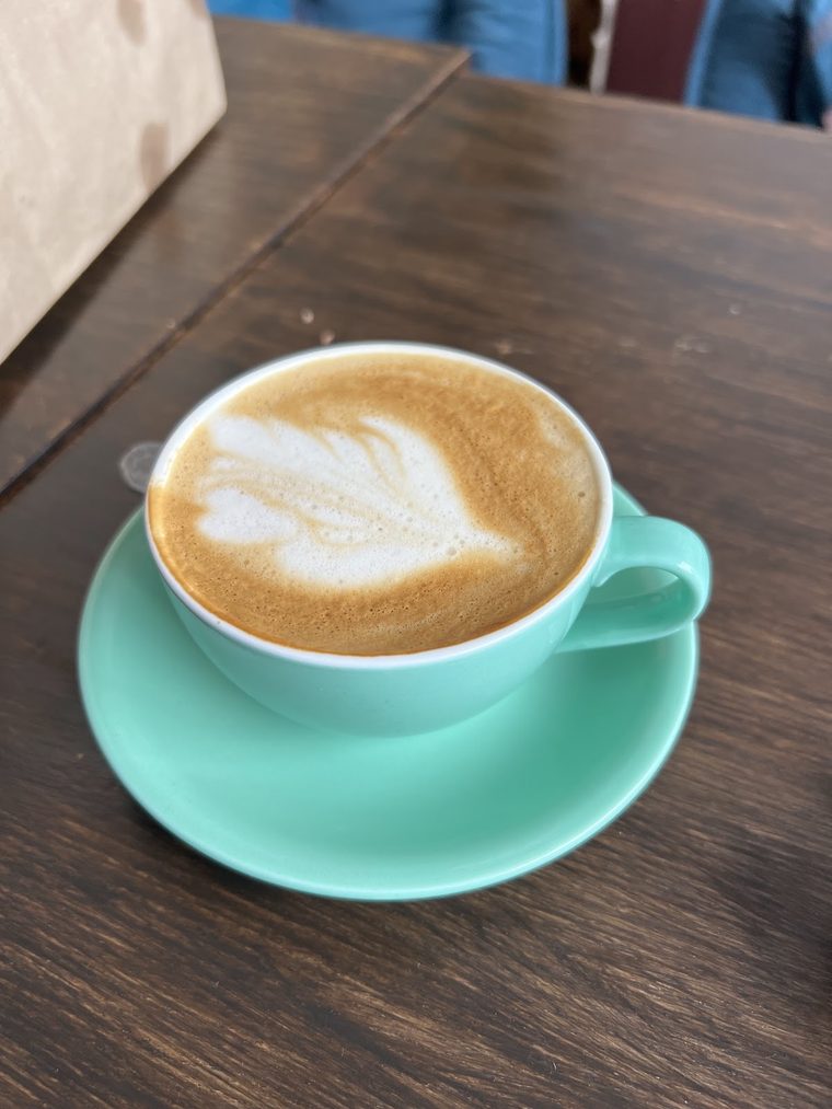 Flat white with rosetta latte art in a mint green cup