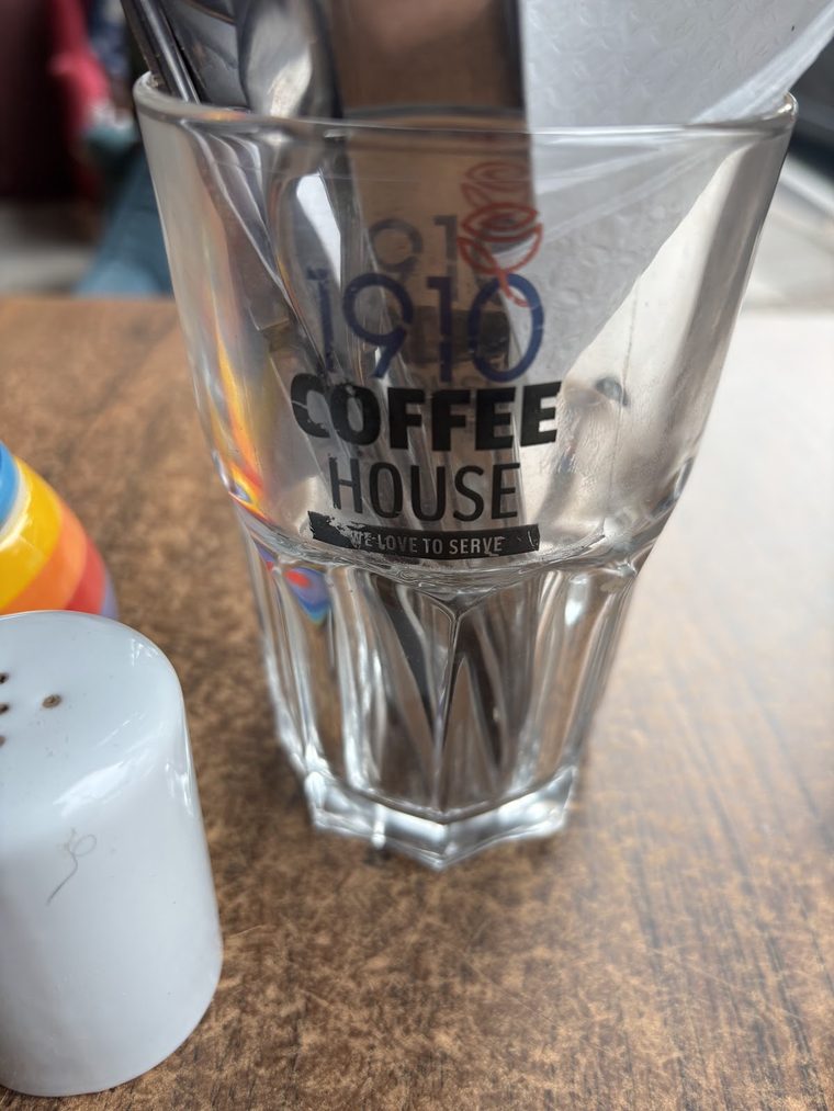 A branded 1910 Coffee House pint glass on a wooden table